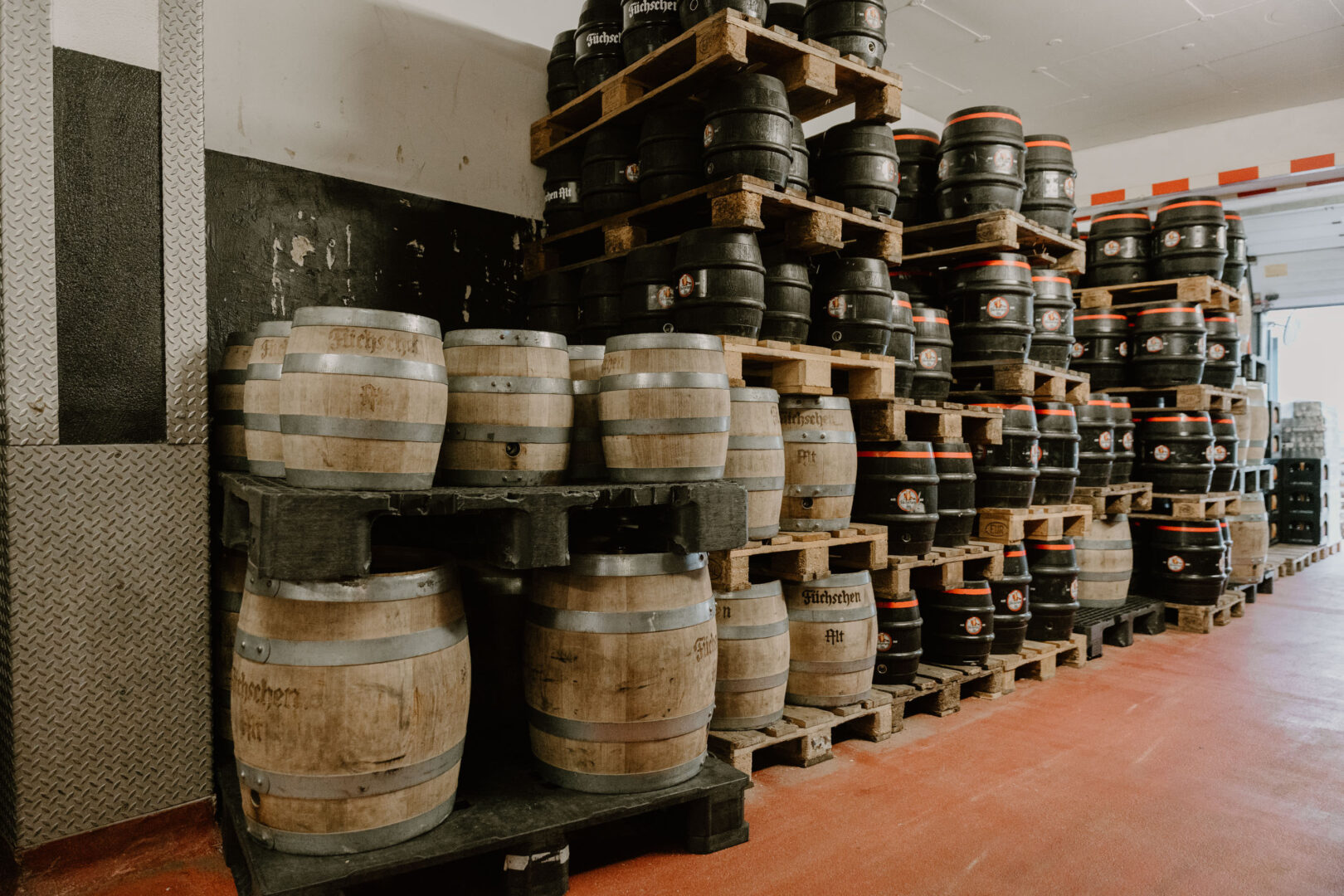 Man sieht links an der Wand aufgereiht und gestapelt: Fässer der Altbierbrauerei Füchschen.