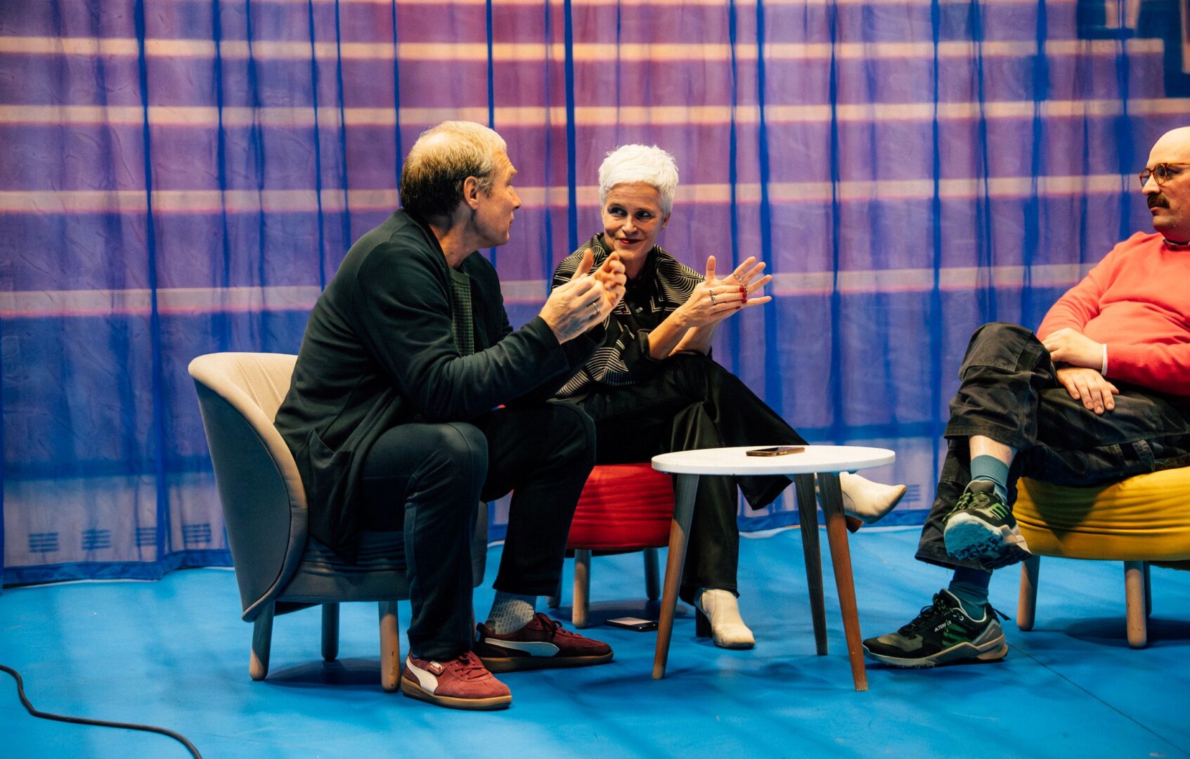 Im Interview: Stefan, Birgit & Clemens sitzen auf niedrigen Sesseln auf der Bühne.