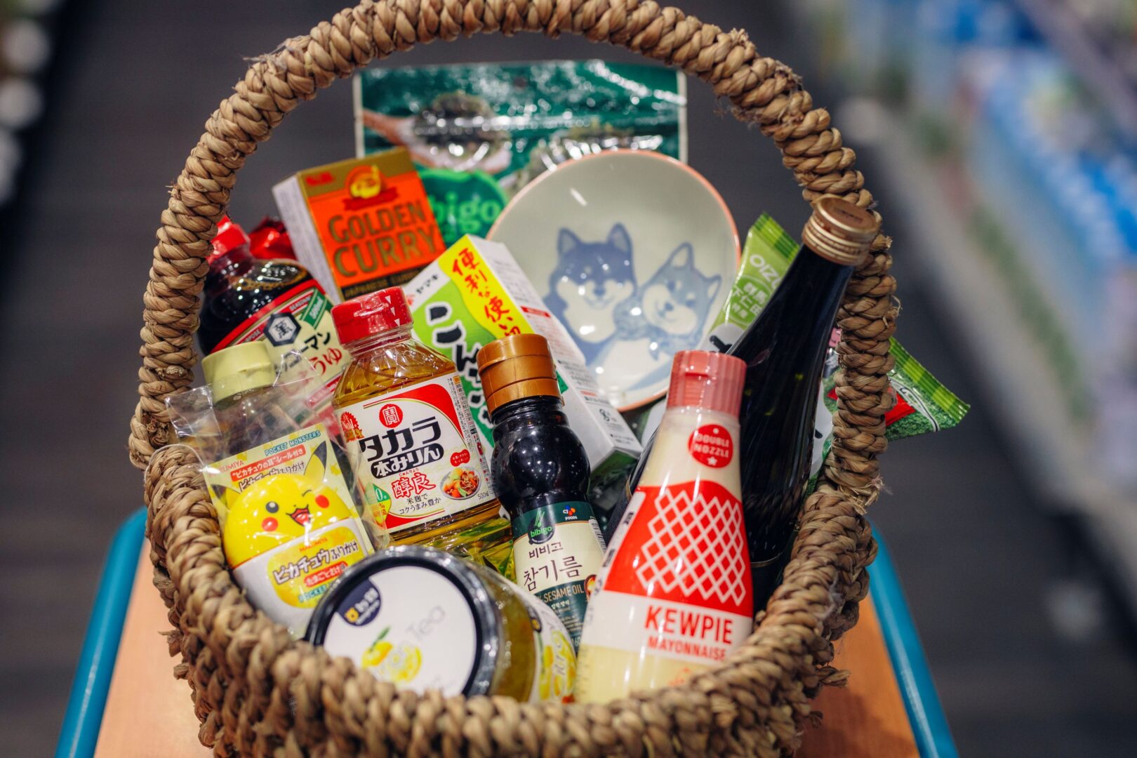 Man sieht den gefüllten Weidekorb mit einer Reisschale, Kewpie-Mayonnaise und vieles mehr.