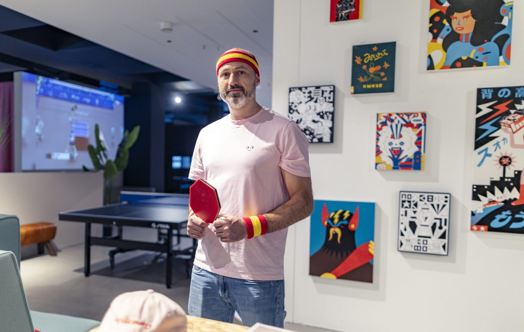 Balla Balla: Alain Bieber mit einem sechseckigen Tischtennisschläger steht vor Holzdrucken von Roman Klonek.