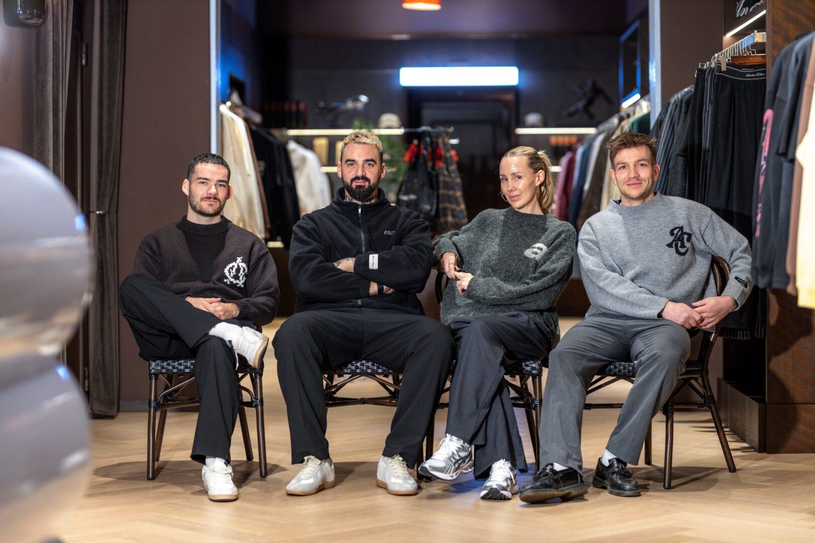Another Cotton Lab: Die vier Macher*innen sitzen auf Stühlen, im Hintergrund der Store.