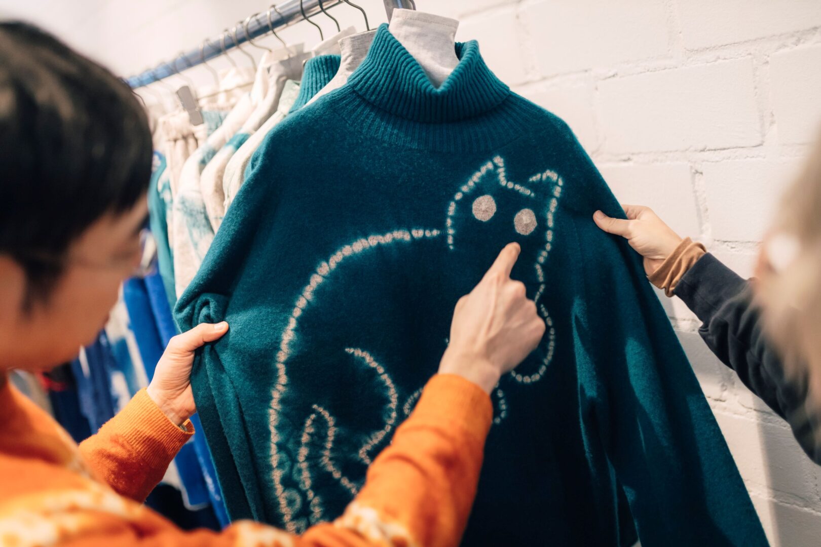 Hiro erläutert das Verfahren Shibori anhand eines Pullovers mit einem Katzenmotiv.