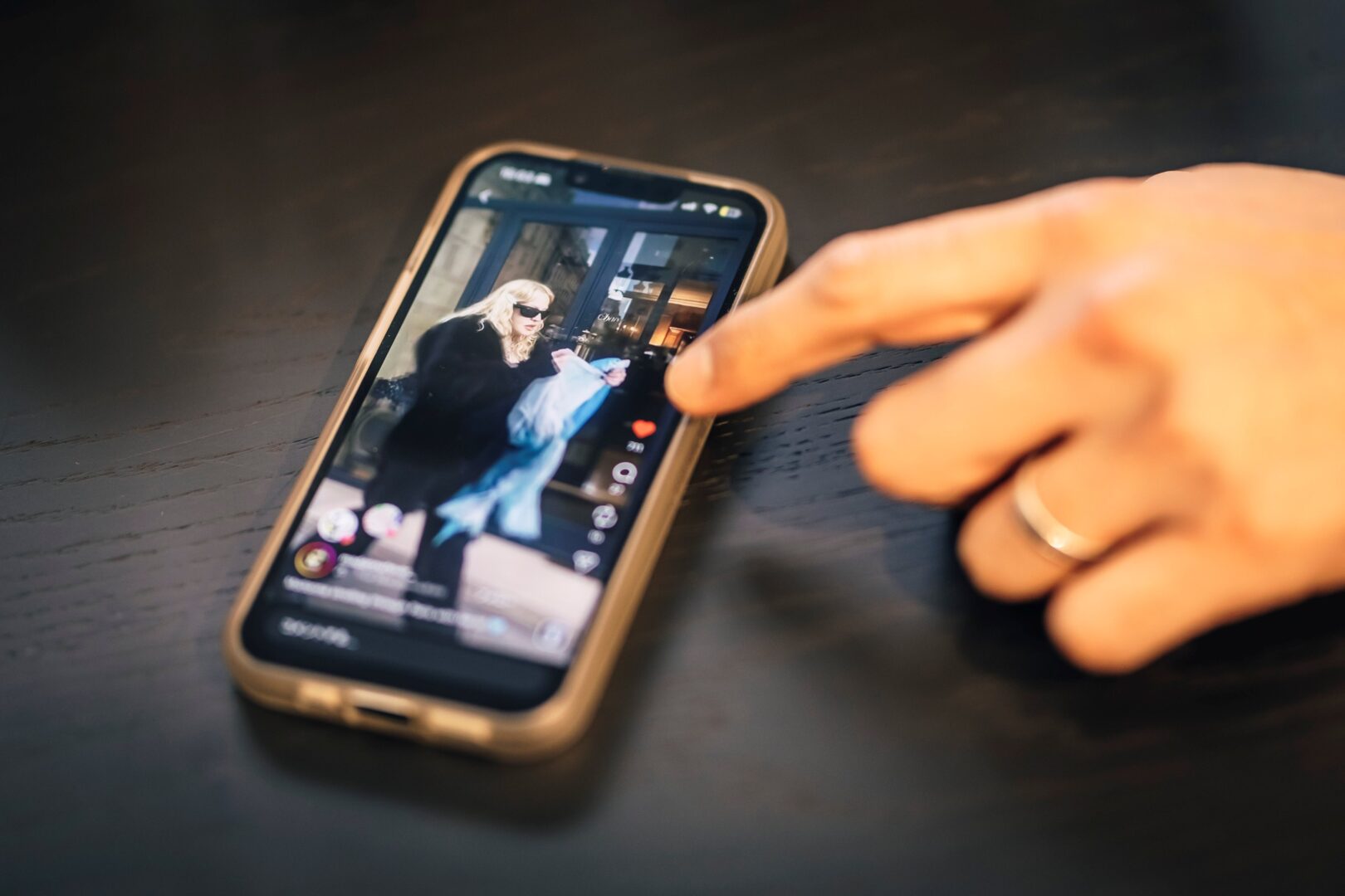 Man sieht Hiros Hand, die auf ein Foto auf dem Handy deutet, worauf man Madonna sieht, die einen Schal von Suzusan trägt.