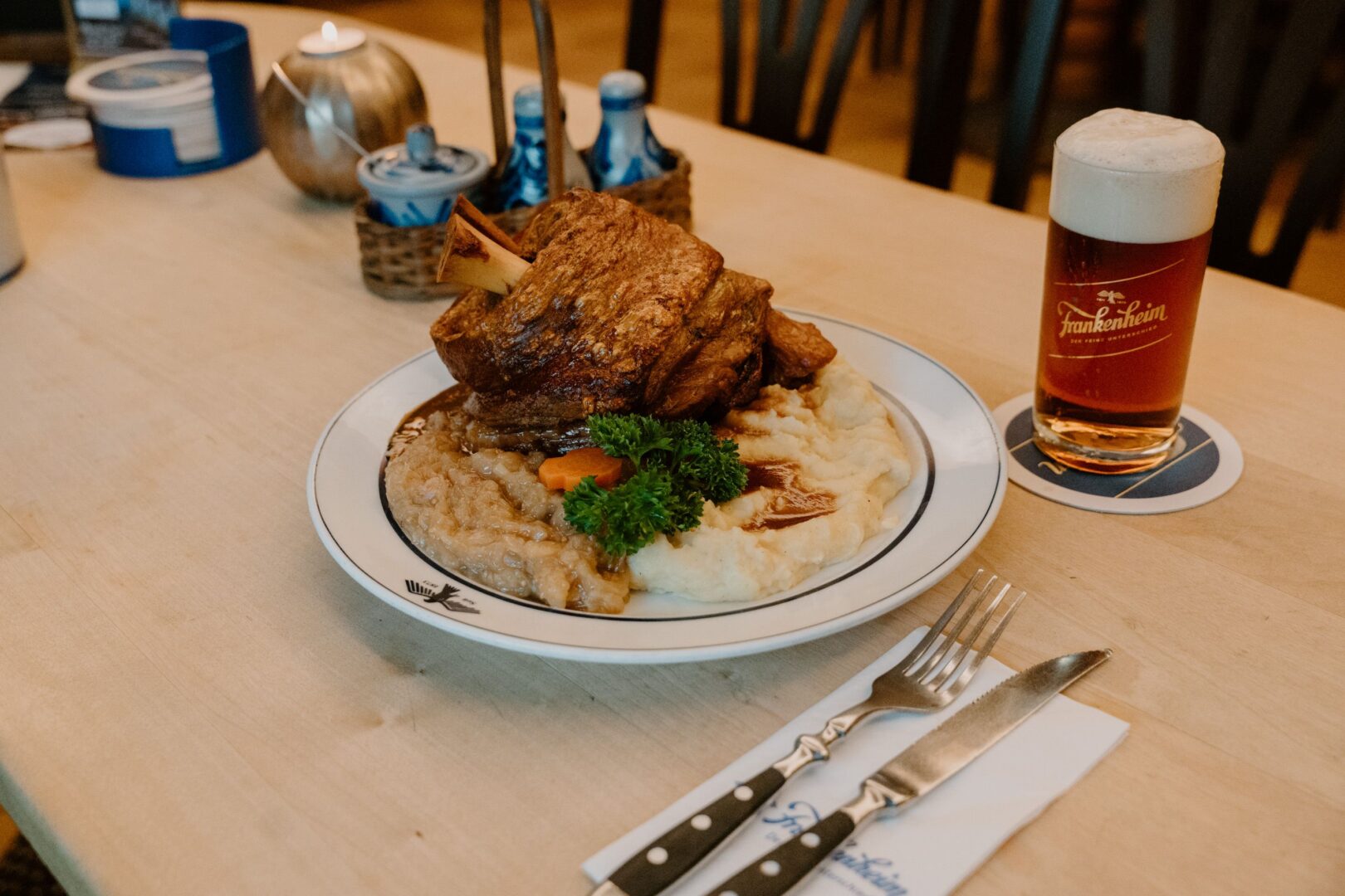 Das Brauhaus Düsseldorf Frankenheim: Man sieht eine gegrillte Schweinshaxe mit Sauerkraut und Kartoffelpüree. 