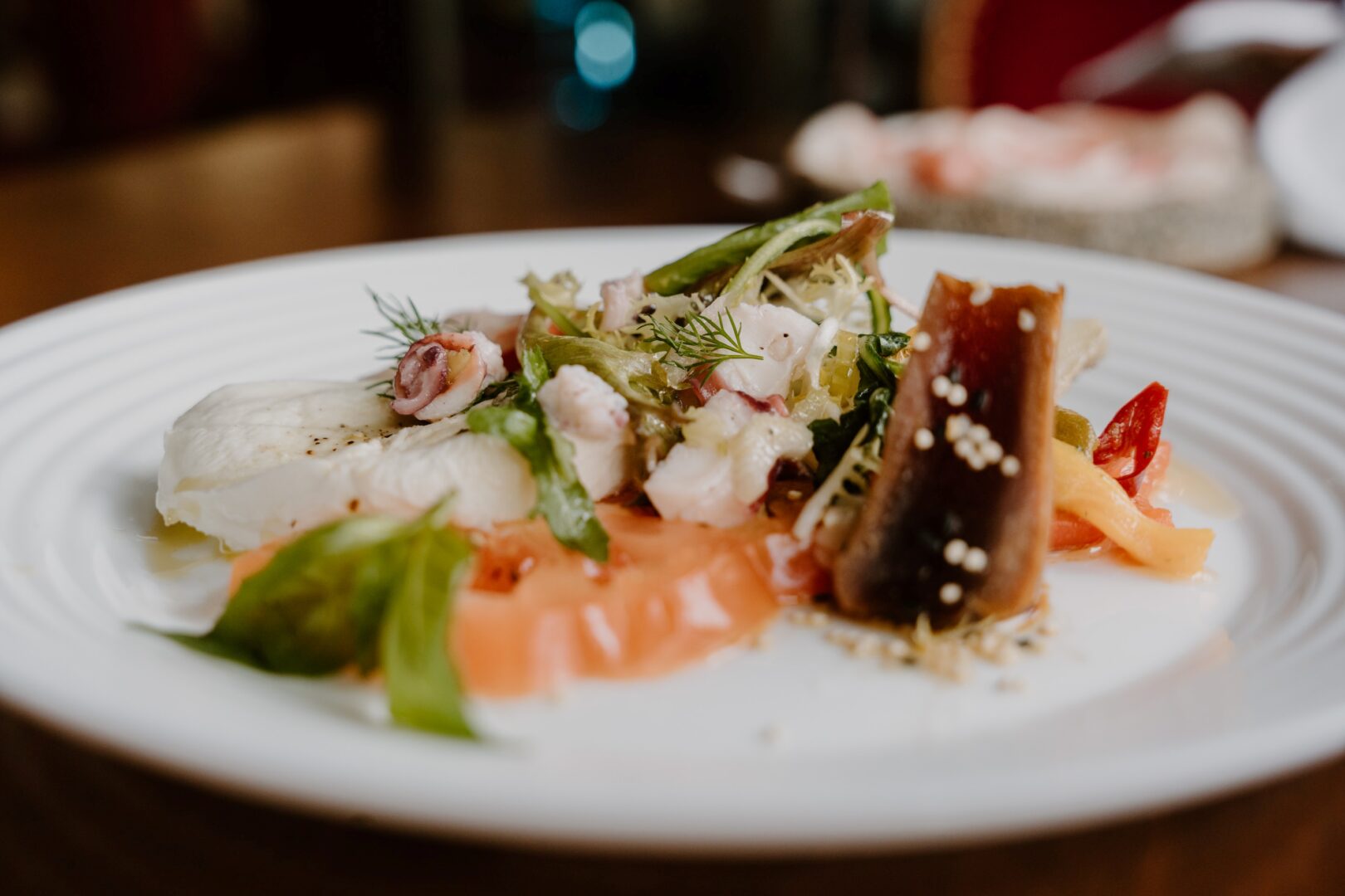 Ein Teller mit Meeresfrüchten im Wine and Dine-Restaurant Primitivo. Man auf dem Teller Lachs-Sashimi, ein kleines Stück kurz angebratenes Thunfischfilet und mehr.