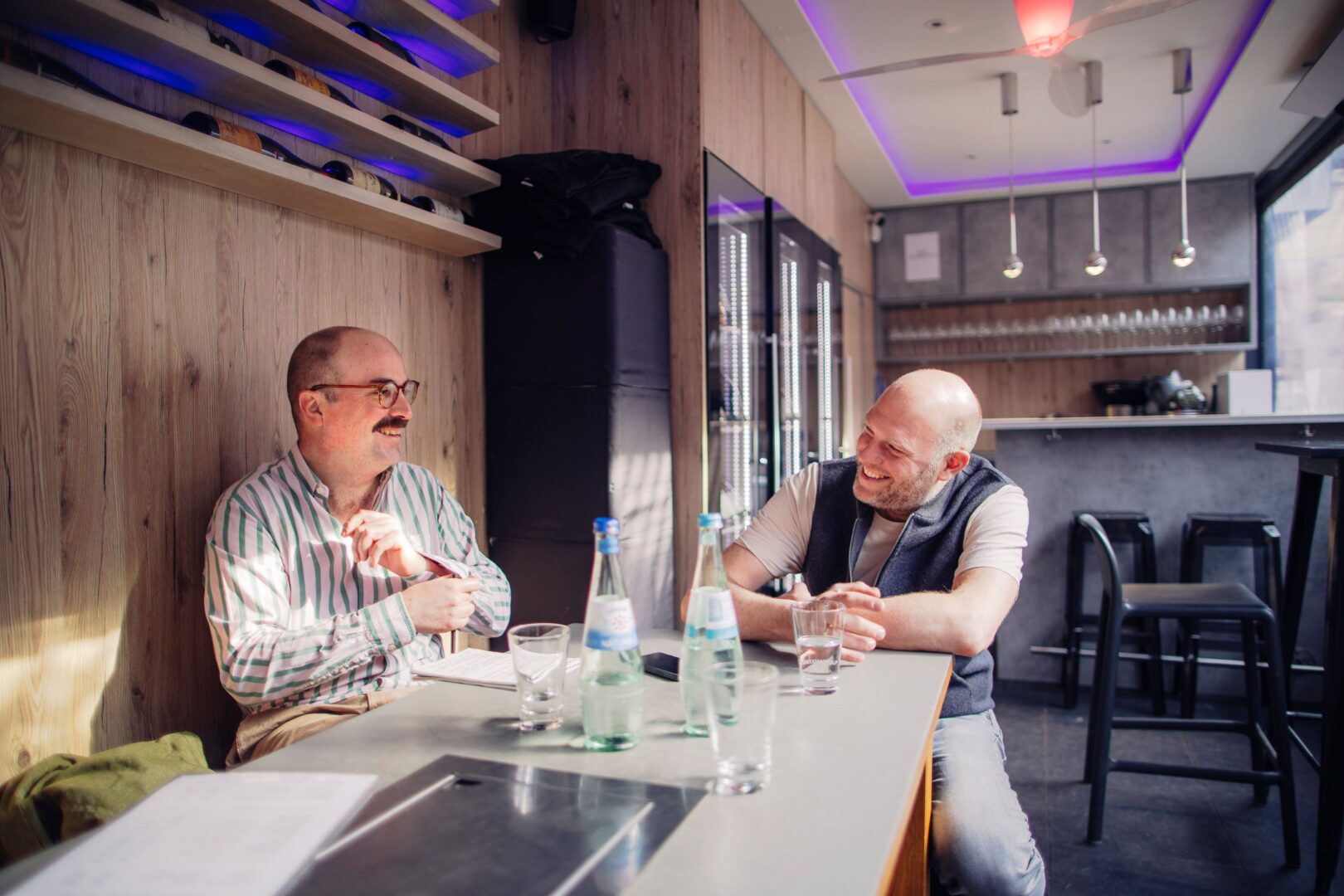 Clemens Henle (links) und Björn Schwethelm sitzen an einem Tisch bei einem Glas Wein und führen das Interview über Concept Riesling.