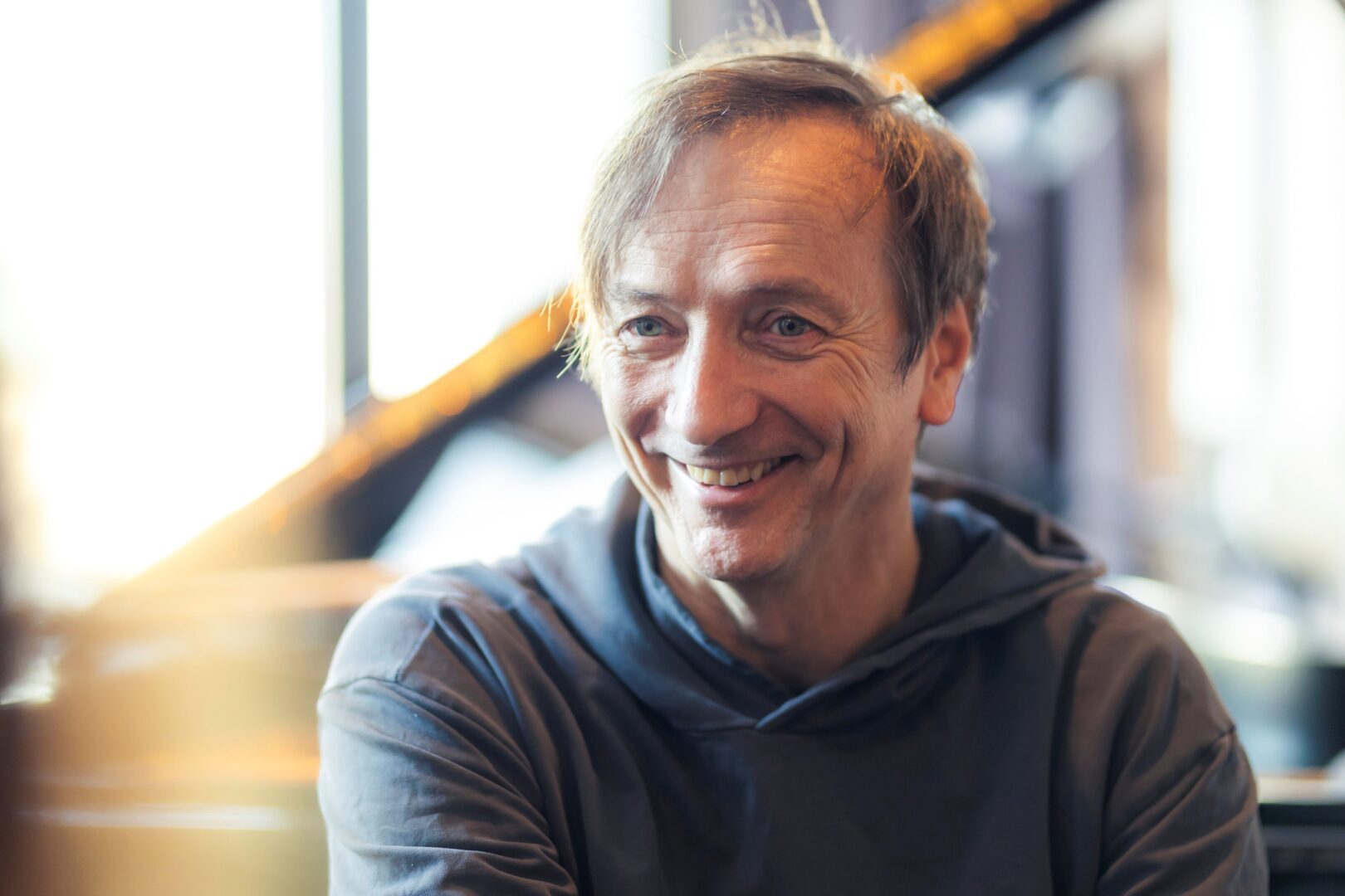 Ein Portrait von Volker Bertelmann, der an der Kamera links vorbeiguckt und lächelt.