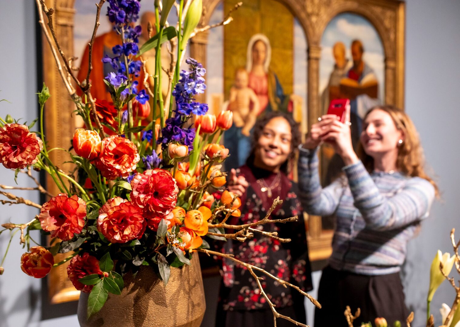 Man sieht zwei Frauen die ein Blumenarrangement im Rahmen von Palastblühen im Kunstpalast fotografieren. 