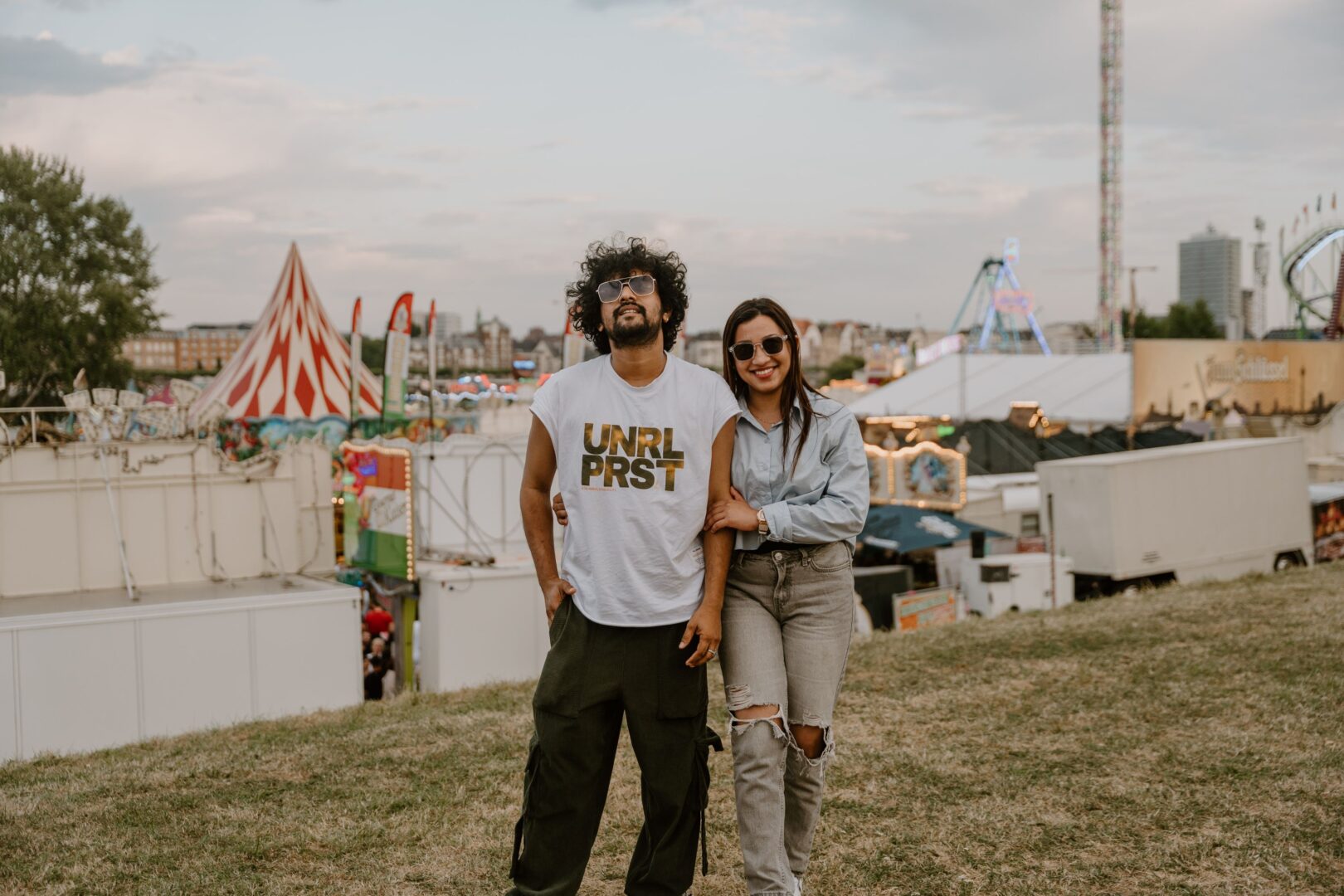 Man sieht ein Pärchen auf der Wiese im Hintergrund die Kirmes in Düsseldorf.